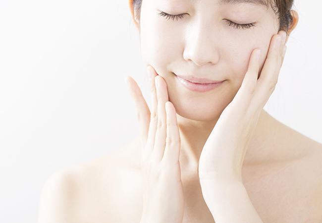 目を閉じ頬に手を添える女性